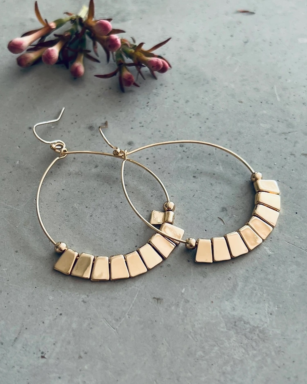 Gold round earrings on grey stone