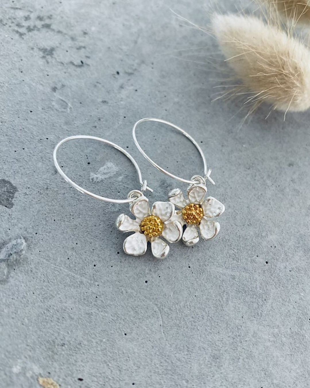 Flower gold hoop earrings on grey stone