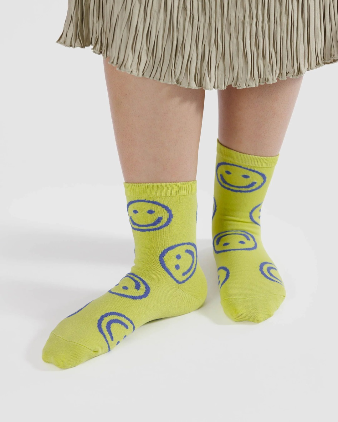 Yellow with blue smiley faces pair of socks on feet