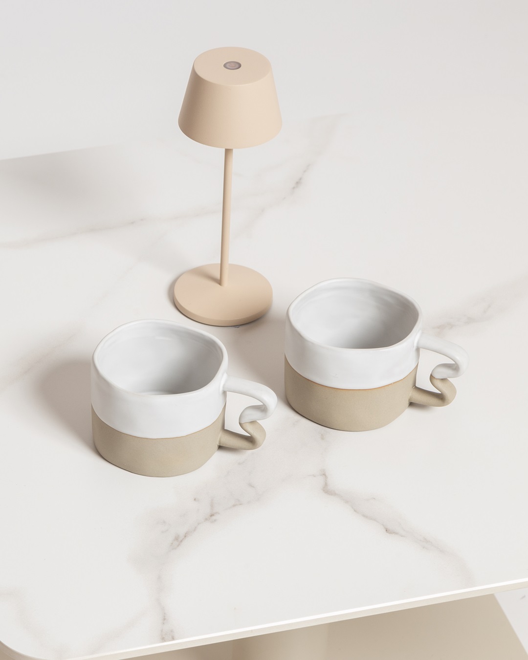 Benni mugs white and sand with squiggle handles with lamp on white table