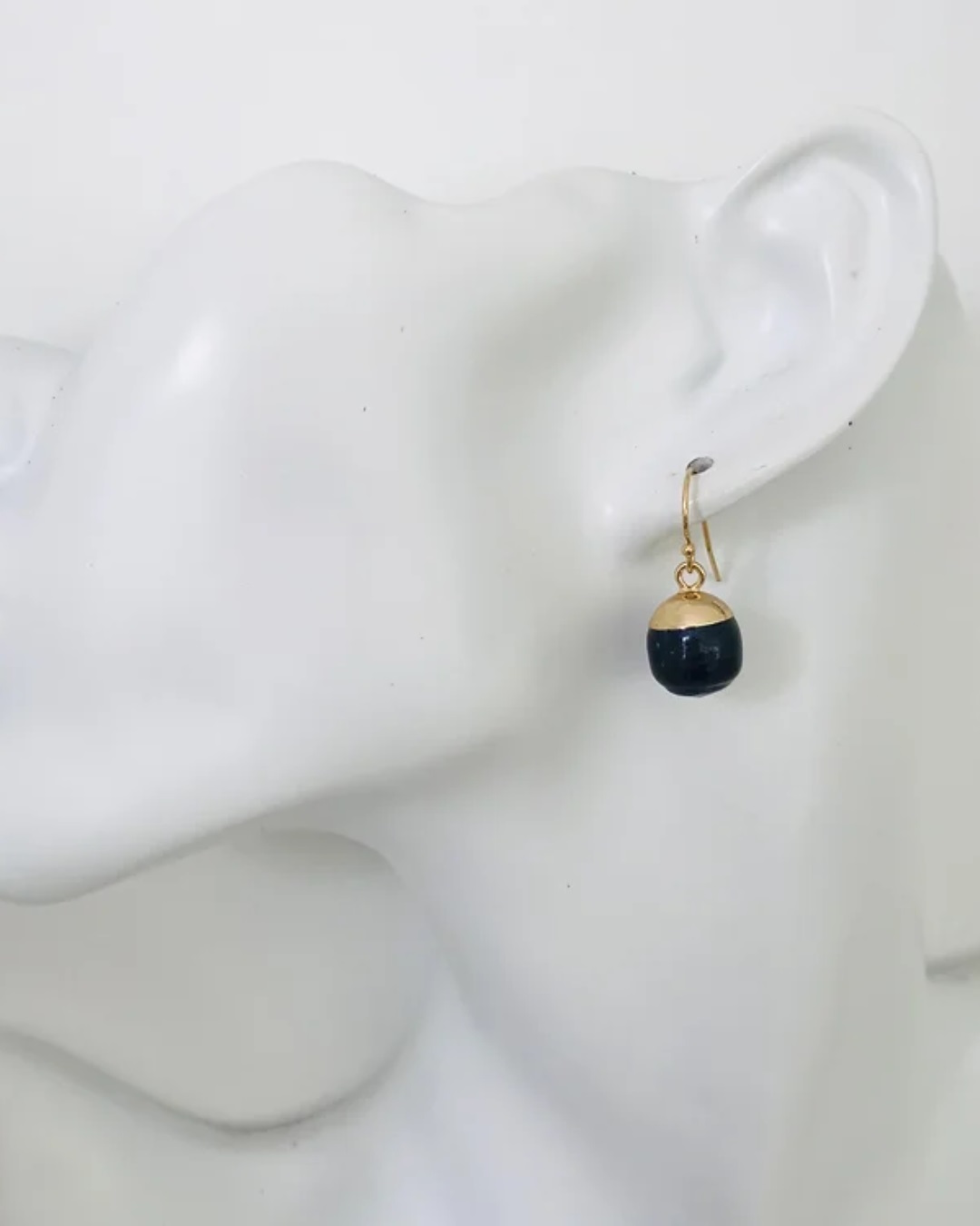 Black acorn pearl bulb earring hanging on ear