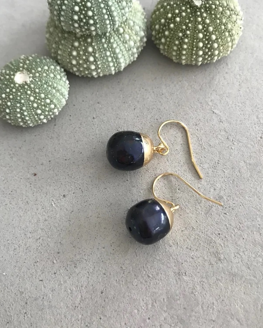 Black acorn pearl bulb earrings on grey stone
