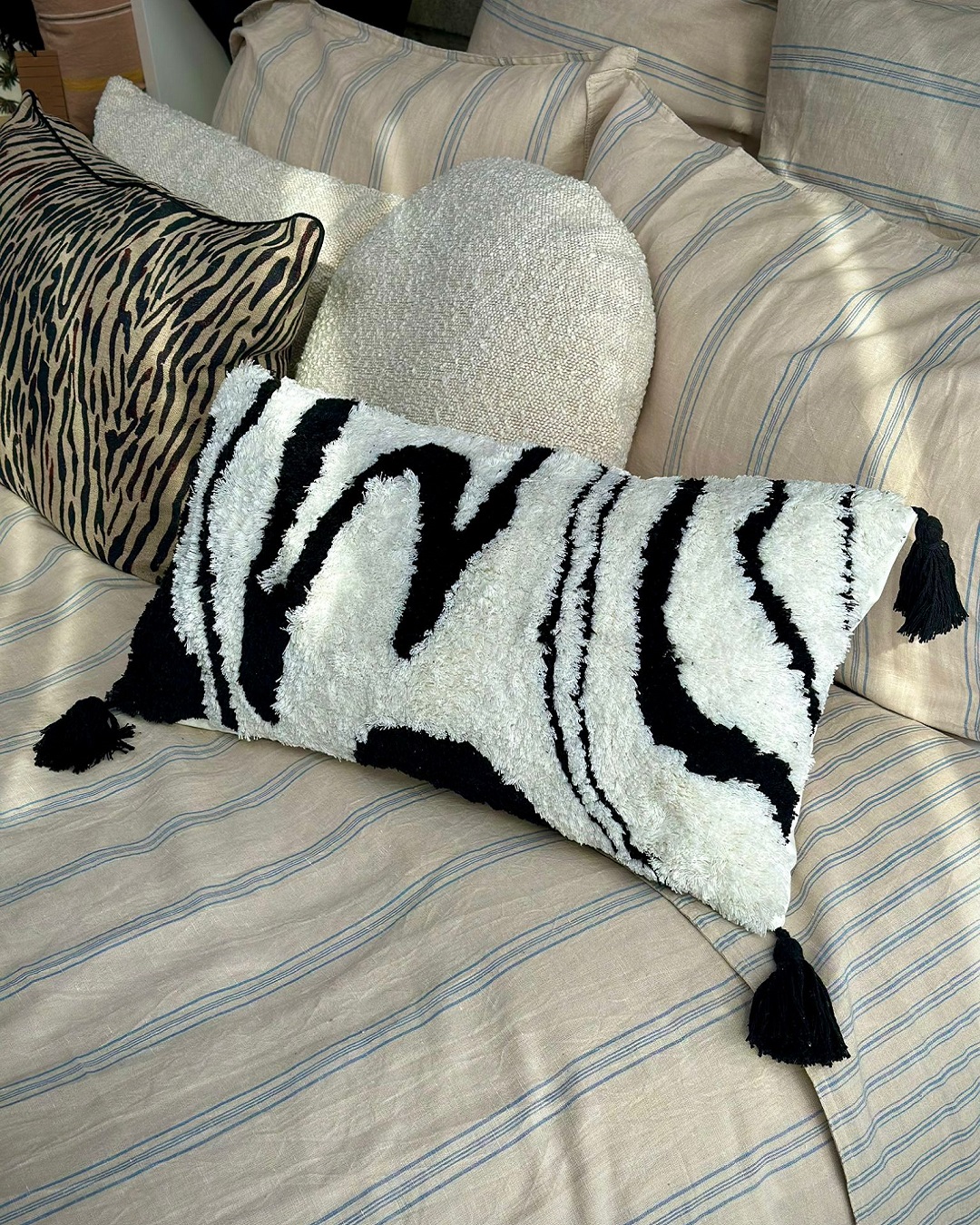 black and white squiggle cushion on bed with black tassels
