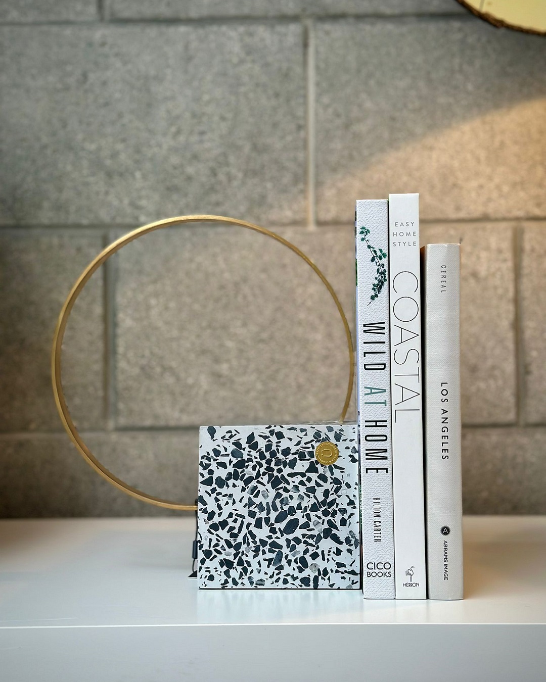Speckled square bookend with brass loop on shelf with books