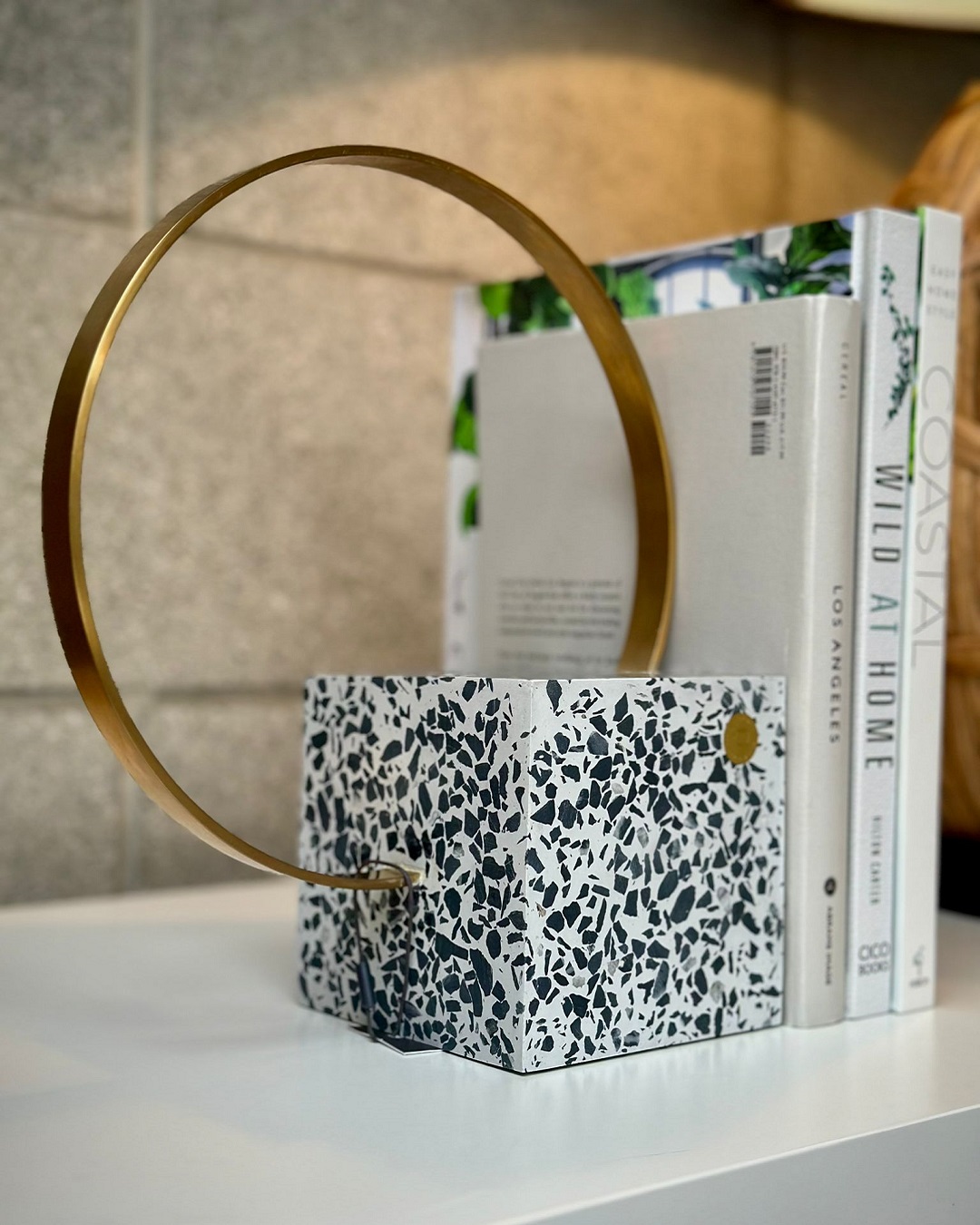 Speckled square bookend with brass loop on shelf with books