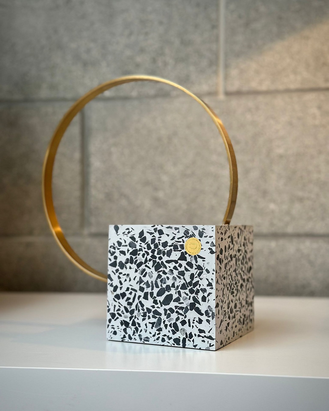 Speckled square bookend with brass loop on shelf