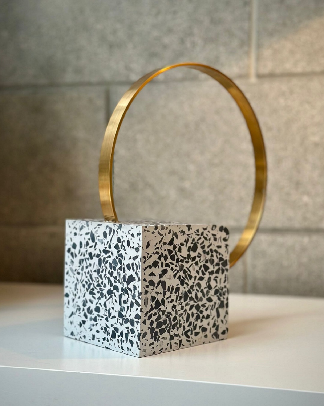 Speckled square bookend with brass loop on shelf