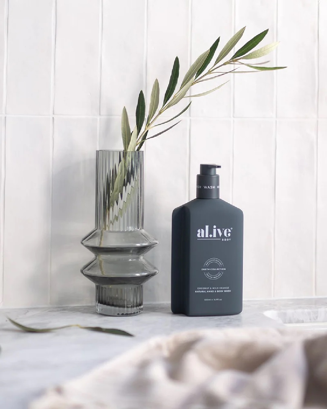Coconut and wild orange al.ive body hand and body wash on bench with vase