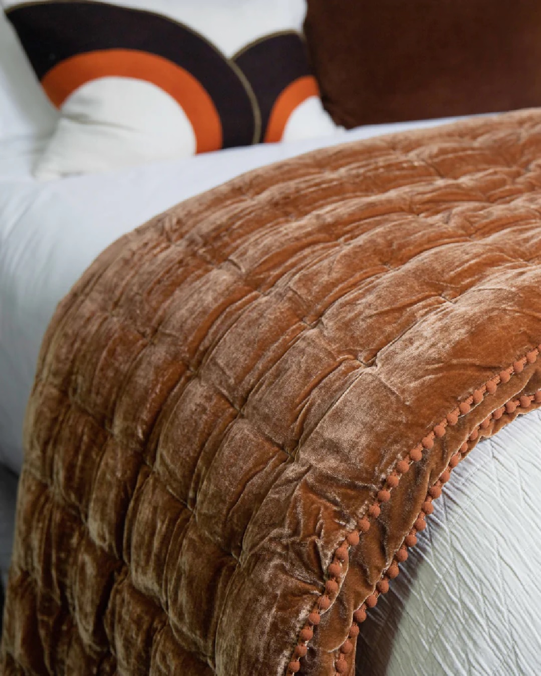 Rusty velvet comforter on white bed