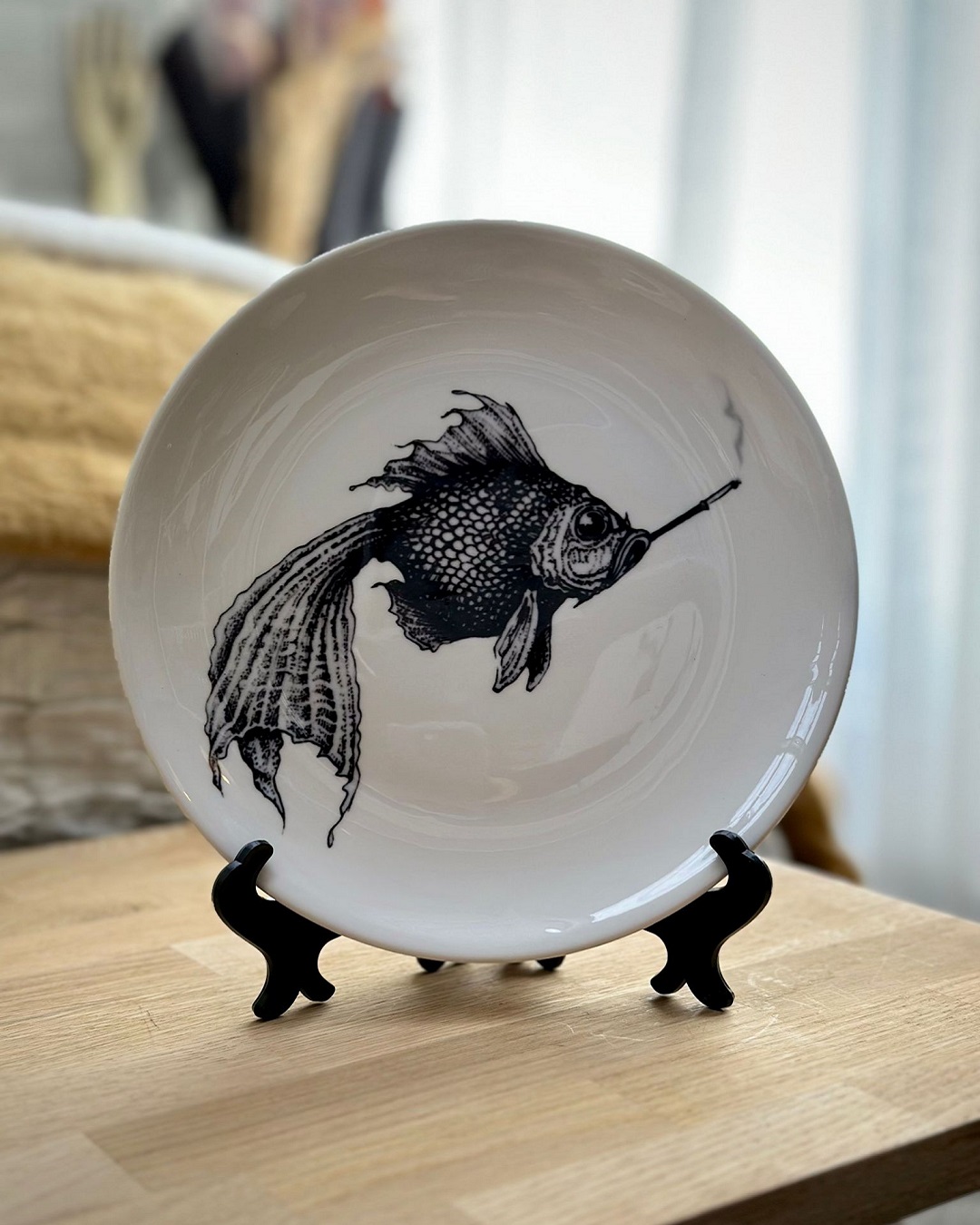 Round white plate in plate stand with black fish on it