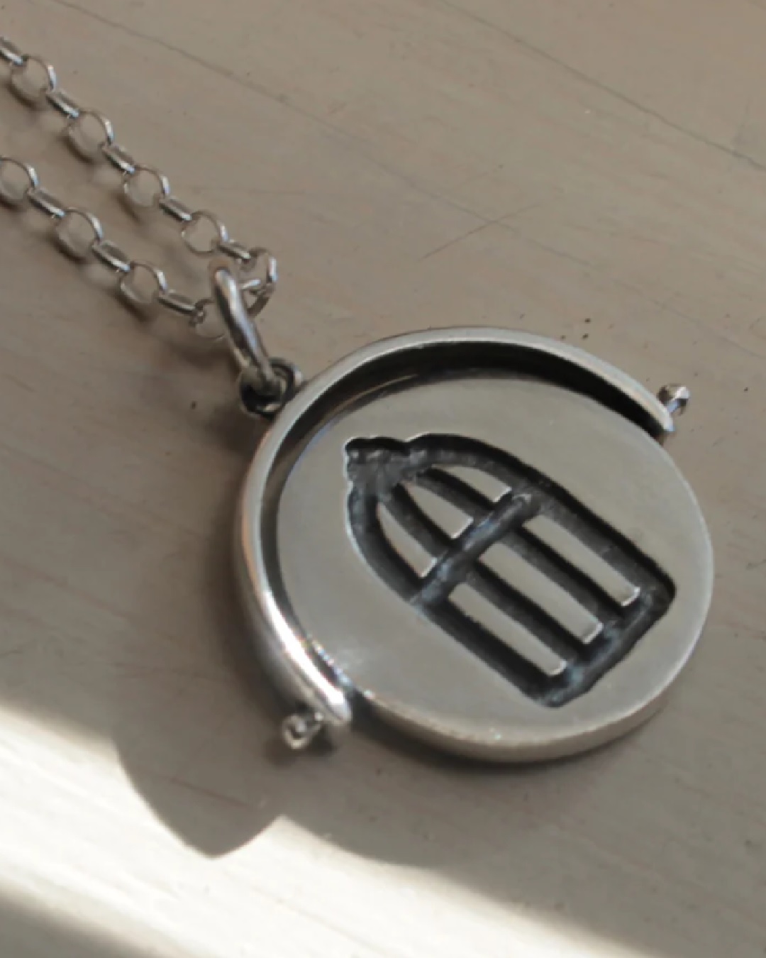 Silver flip circle pendant necklace with a bird cage