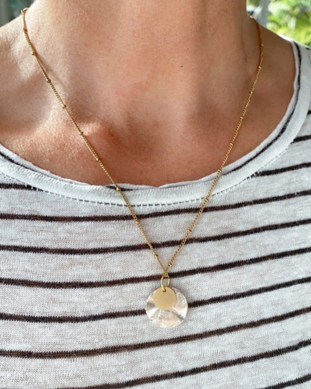 Gold and silver disk necklace around neck