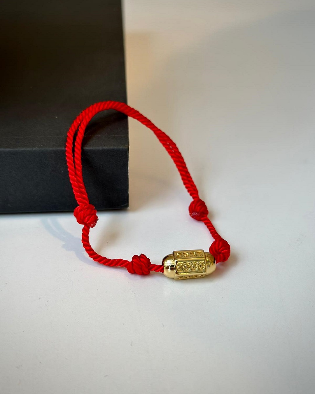 Red woven friendship bracelet with gold plated diamantes on it