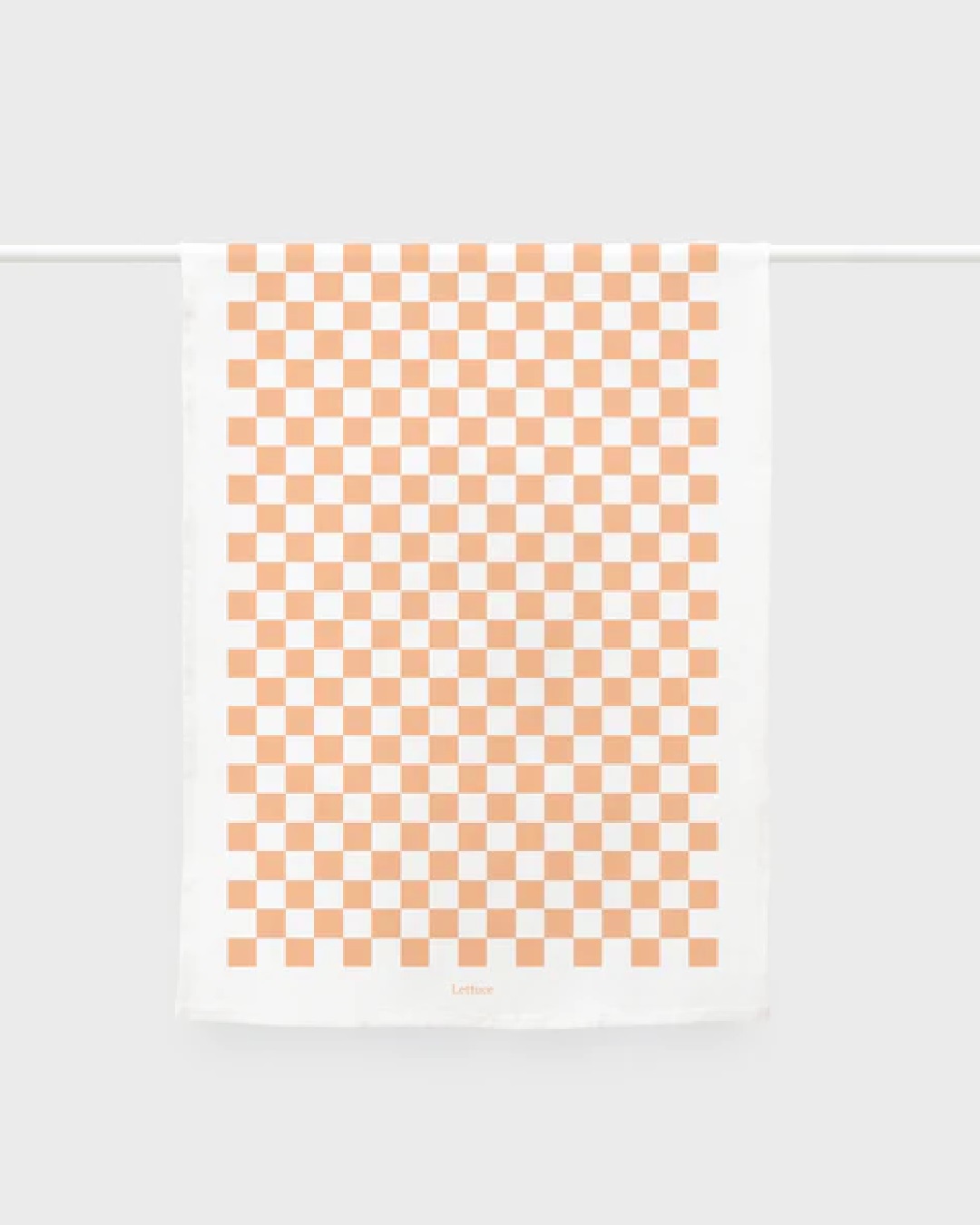 Tea towel hanging on rail with white and peach checks