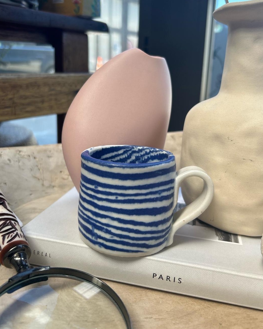 Nerikomi blue striped mug on book with vases