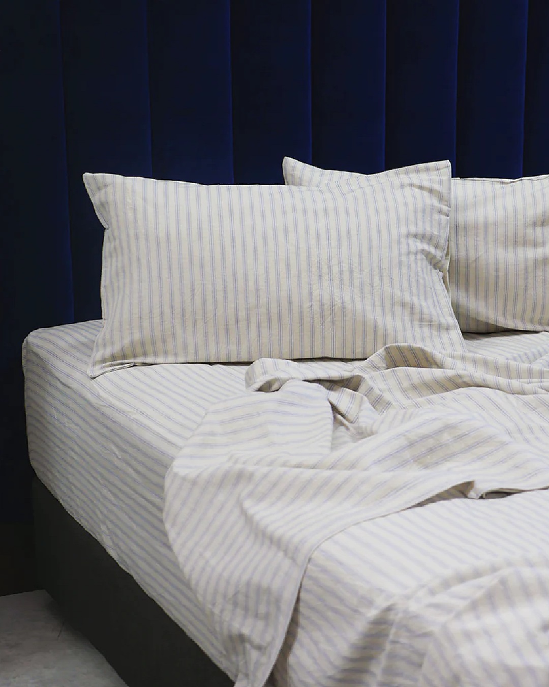 Striped blue and white sheets on bed with pillows