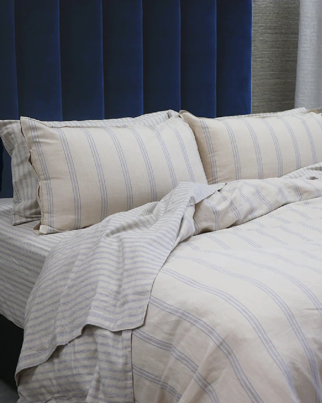 Striped blue and white sheets and duvet on bed with pillows