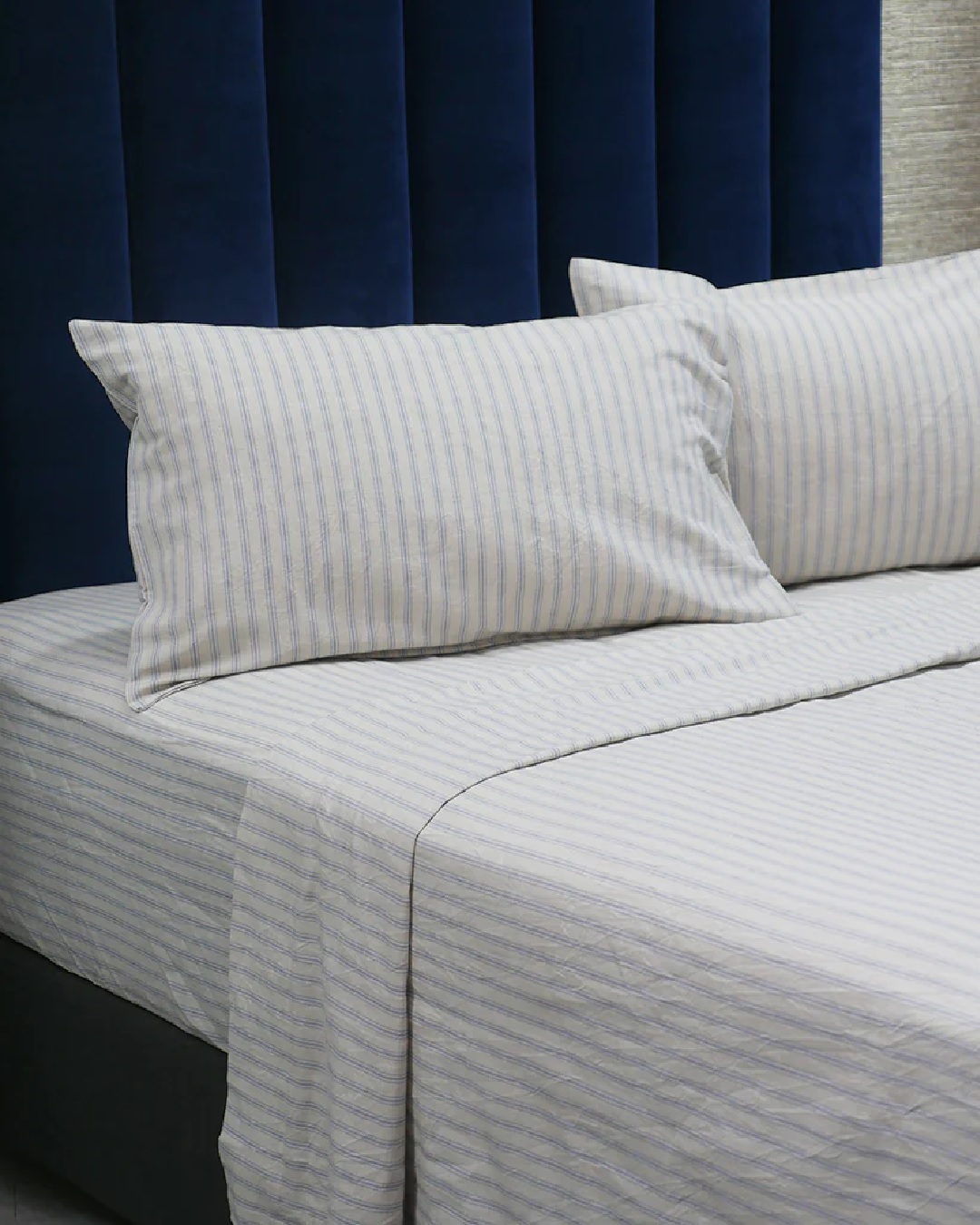 Striped blue and white sheets on bed with pillows