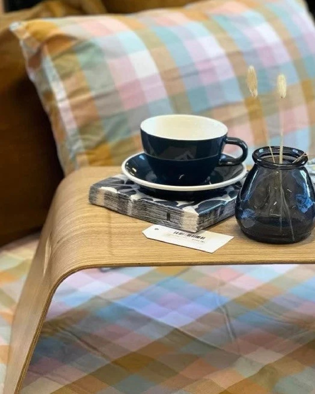 Checkered orange and blue pillow and bedding with coffee and vase on wooden tray