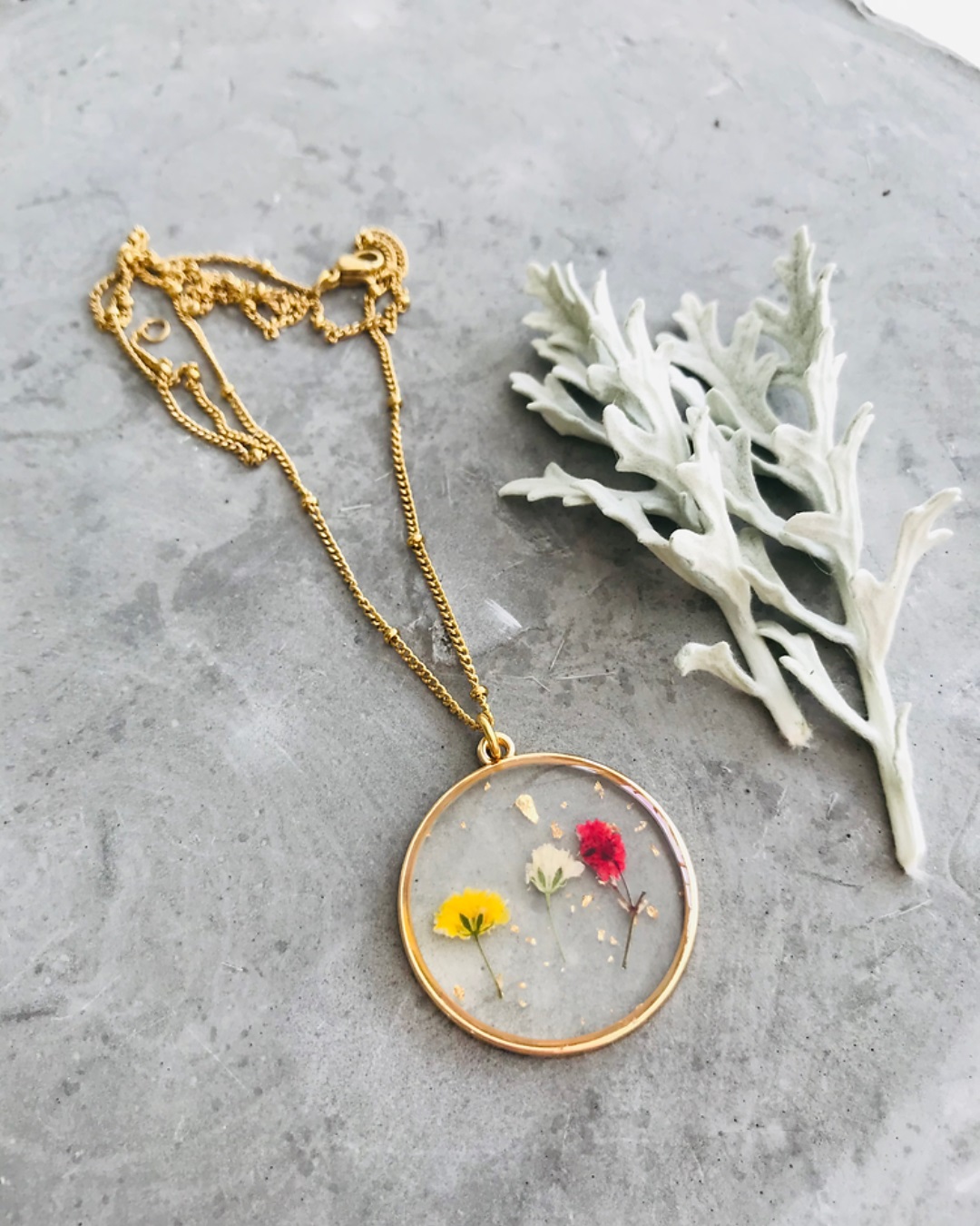 Pressed floral necklace with gold chain on grey stone