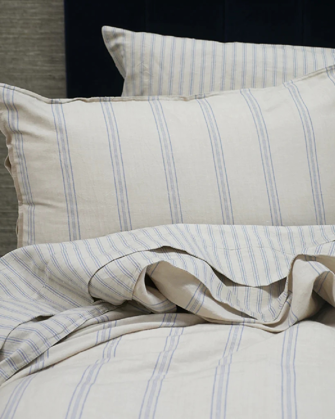 Striped blue and white sheets and duvet on bed with pillows