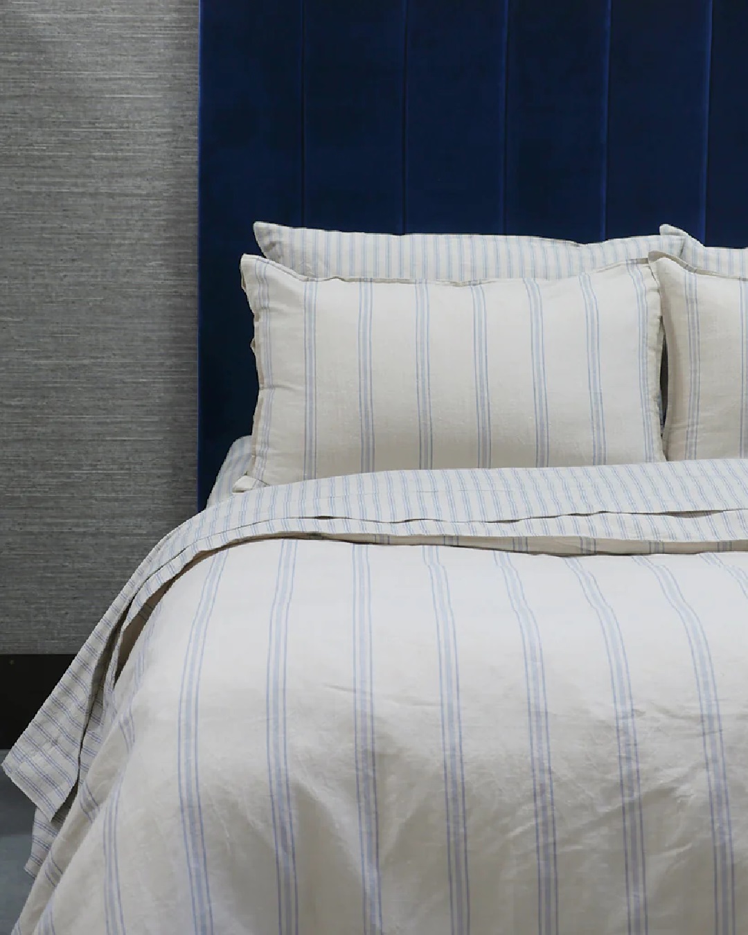Striped blue and white sheets and duvet on bed with pillows
