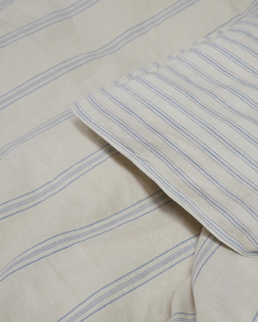 Striped blue and white sheets and duvet on bed