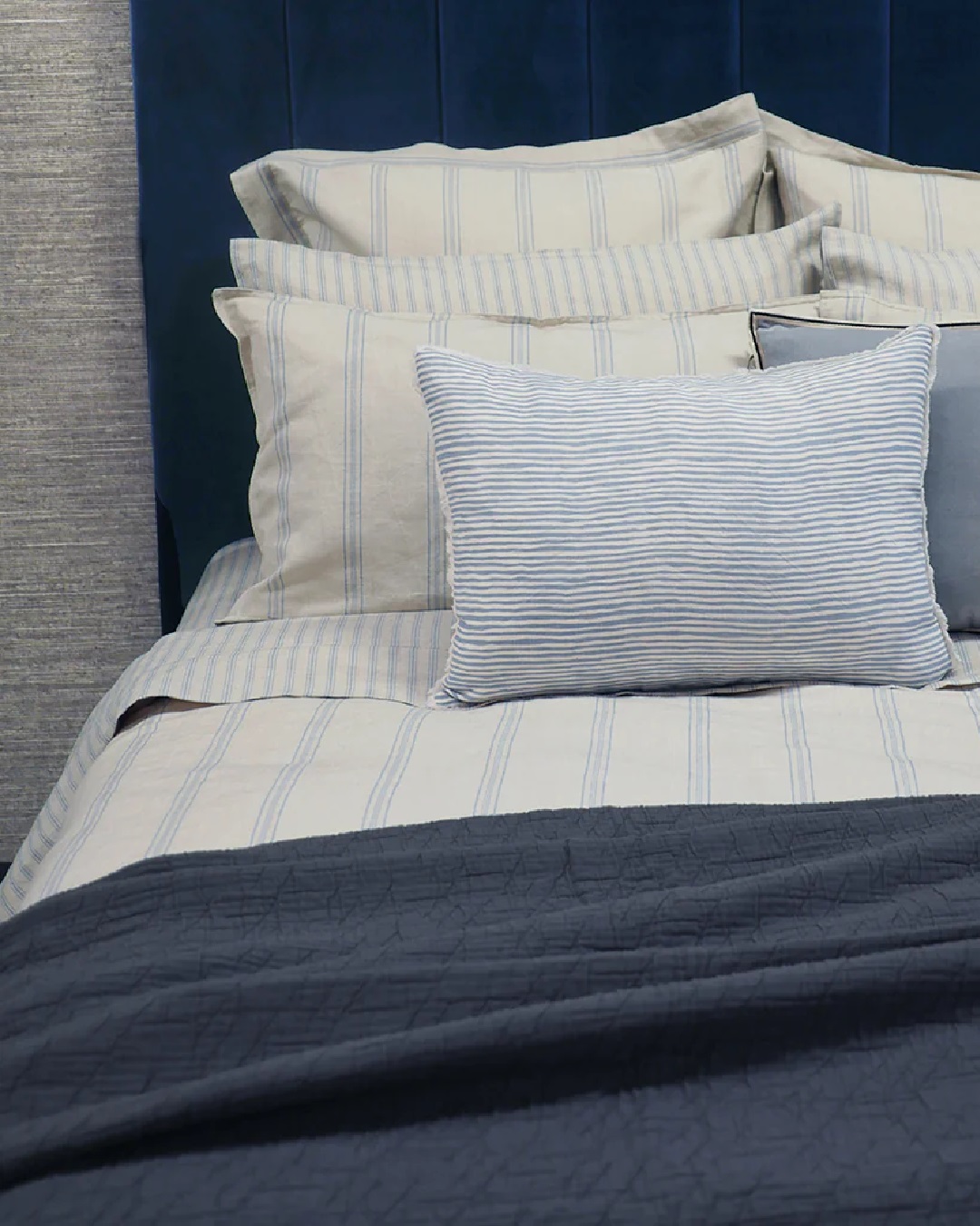 Striped blue and white sheets and duvet on bed with pillows