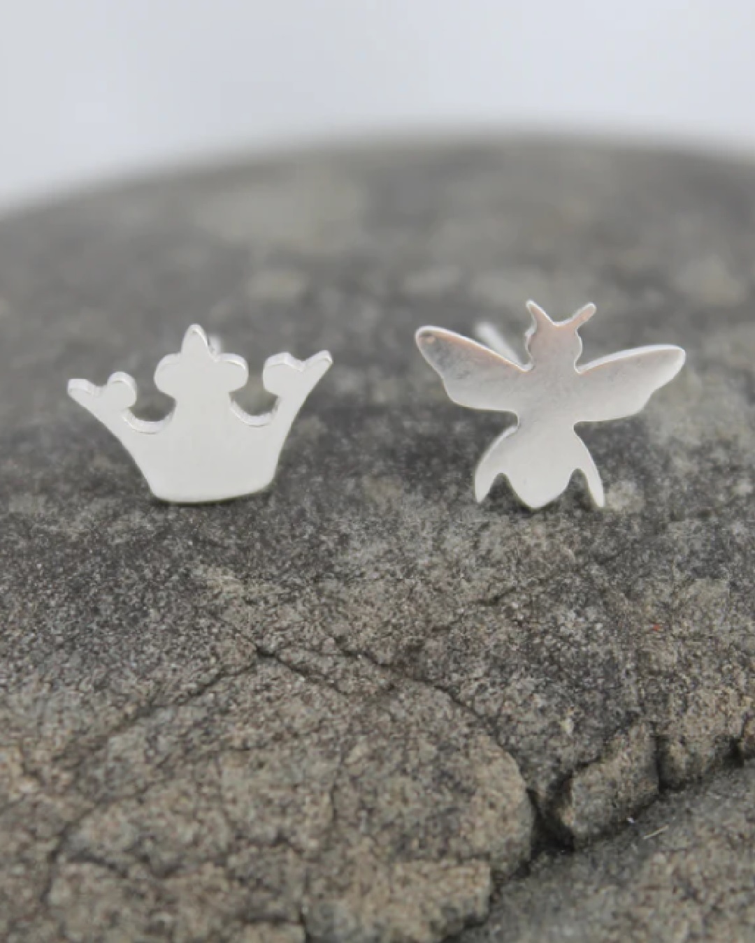 Silver stud earrings one of a crown and one of a bee