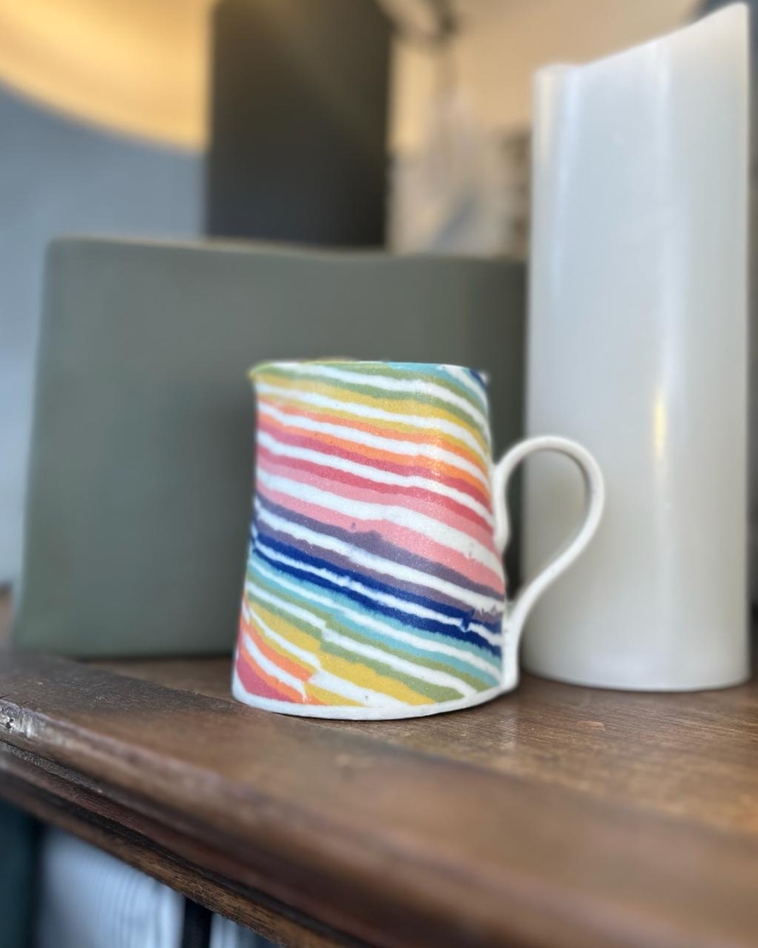 Rainbow striped jug on wooden shelf