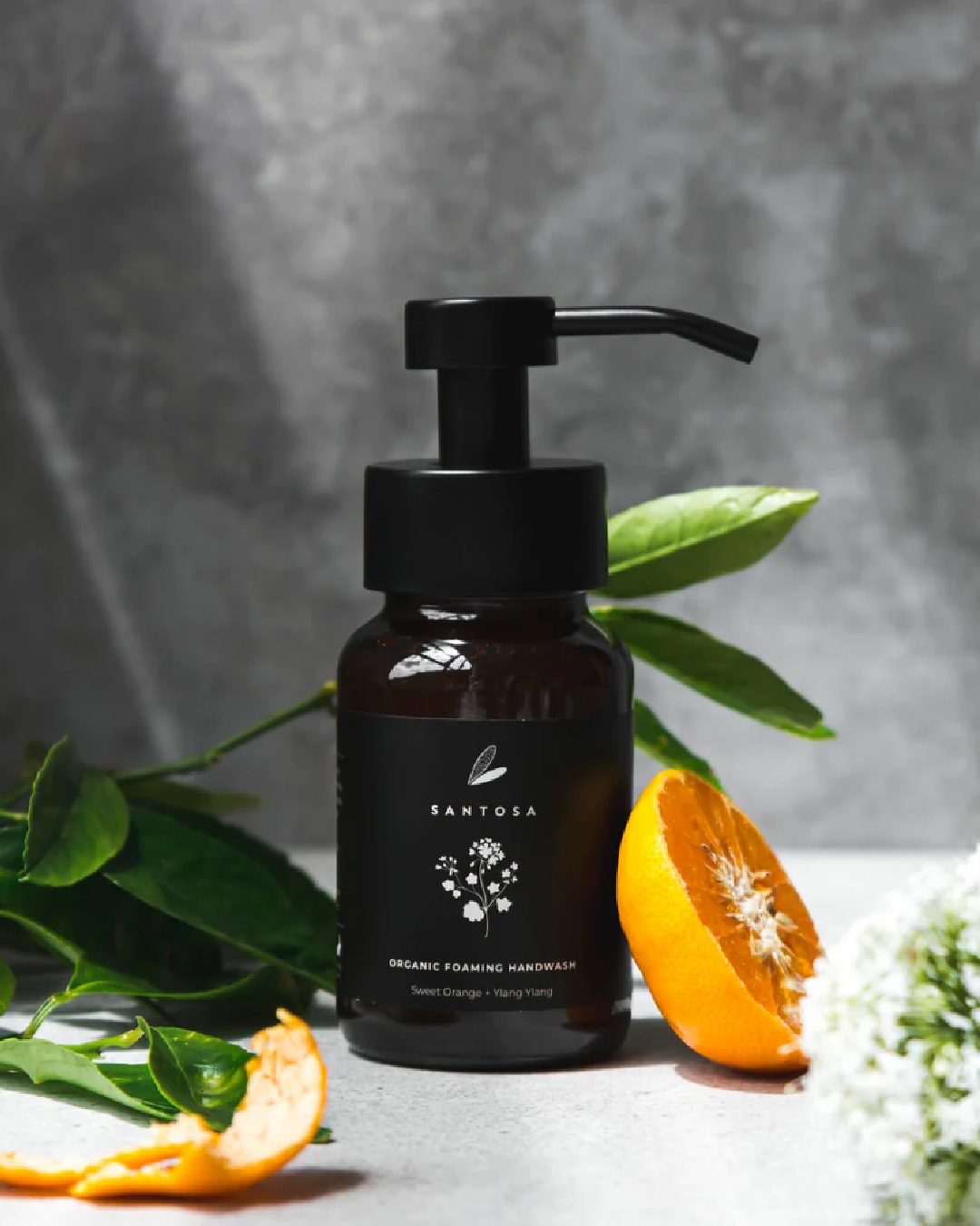 Hand wash pump bottle with orange and ylang ylang aorund it