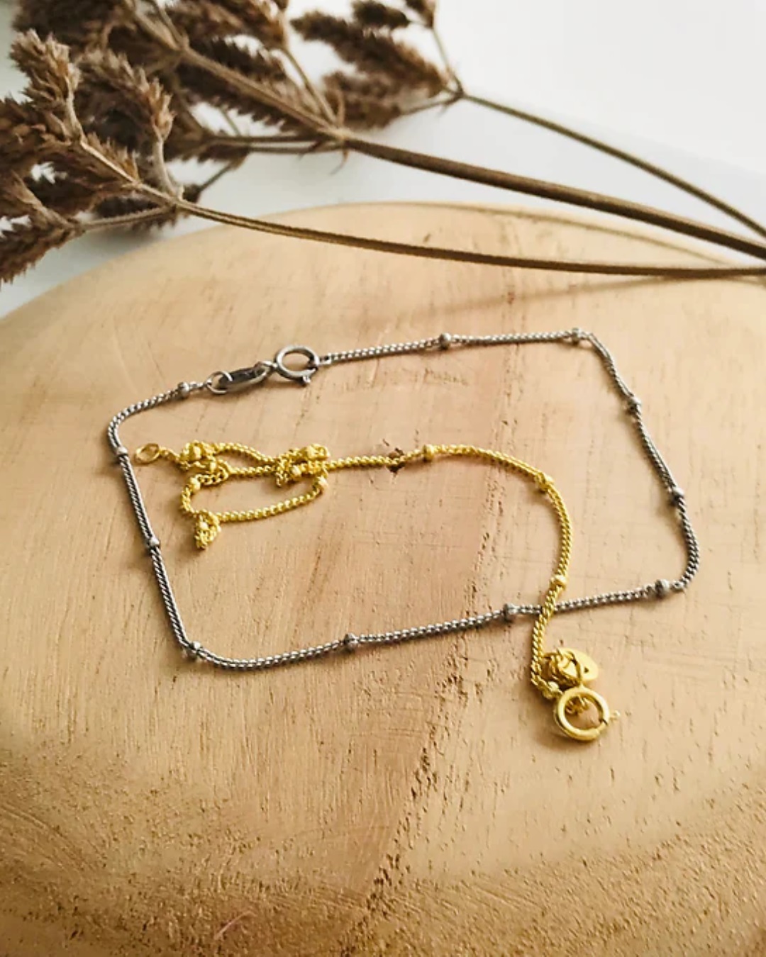 Fine gold and silver chain bracelet on wooden board