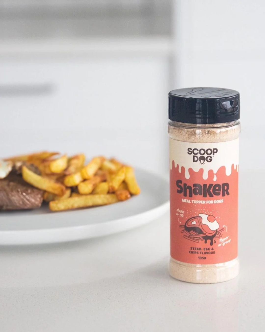 Dog food shaker next to plate with chips and steak
