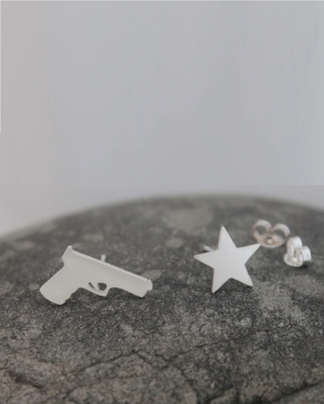 Silver stud earrings one of a gun and one of a star
