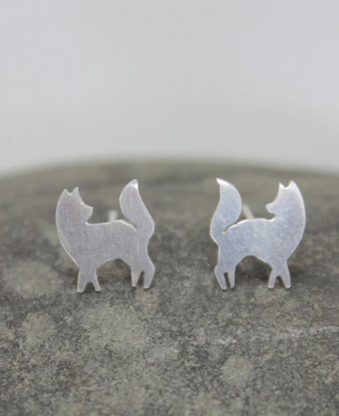 Silver fox stud earrings on rock