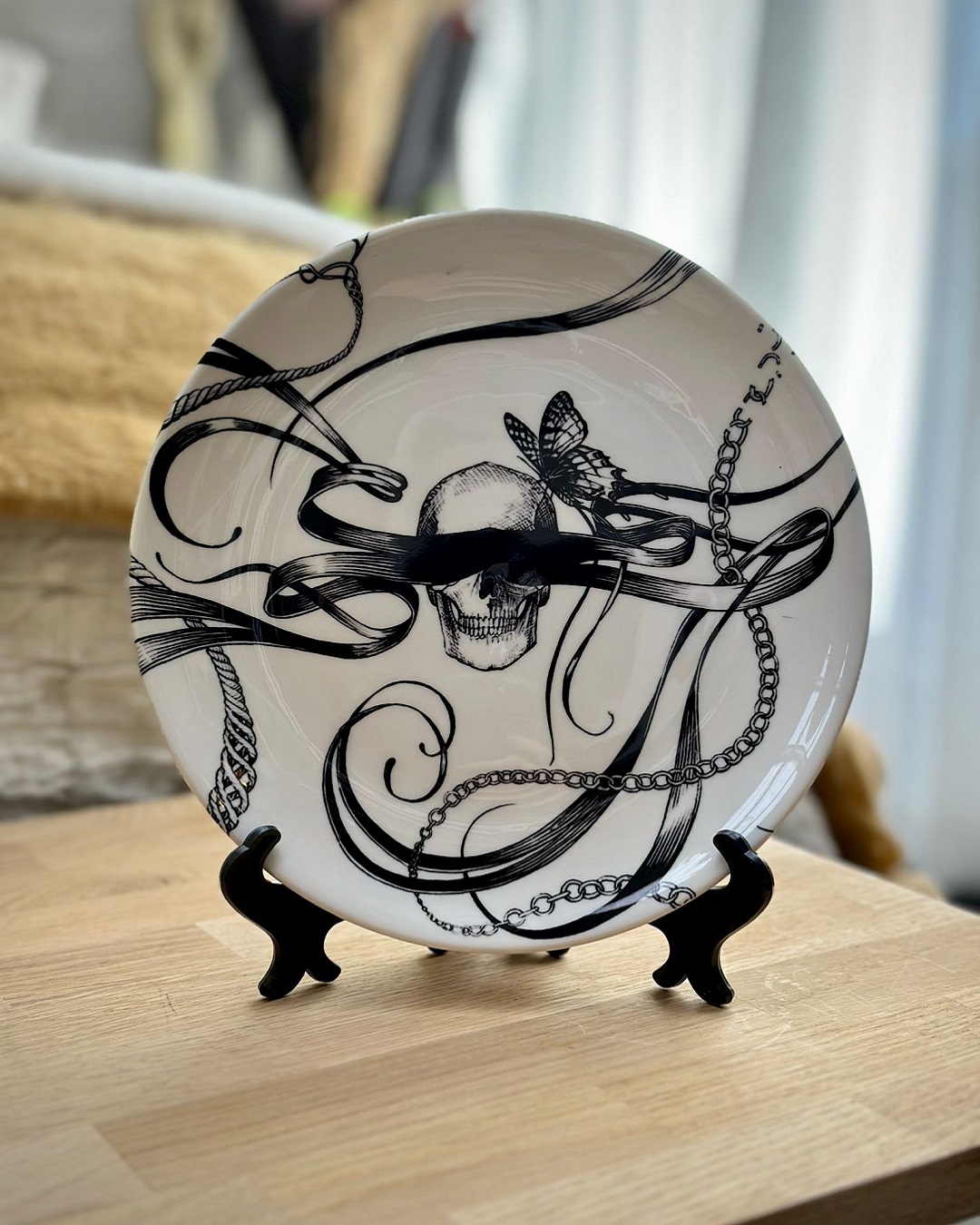 Round white plate in plate stand with black skull and ribbons on it