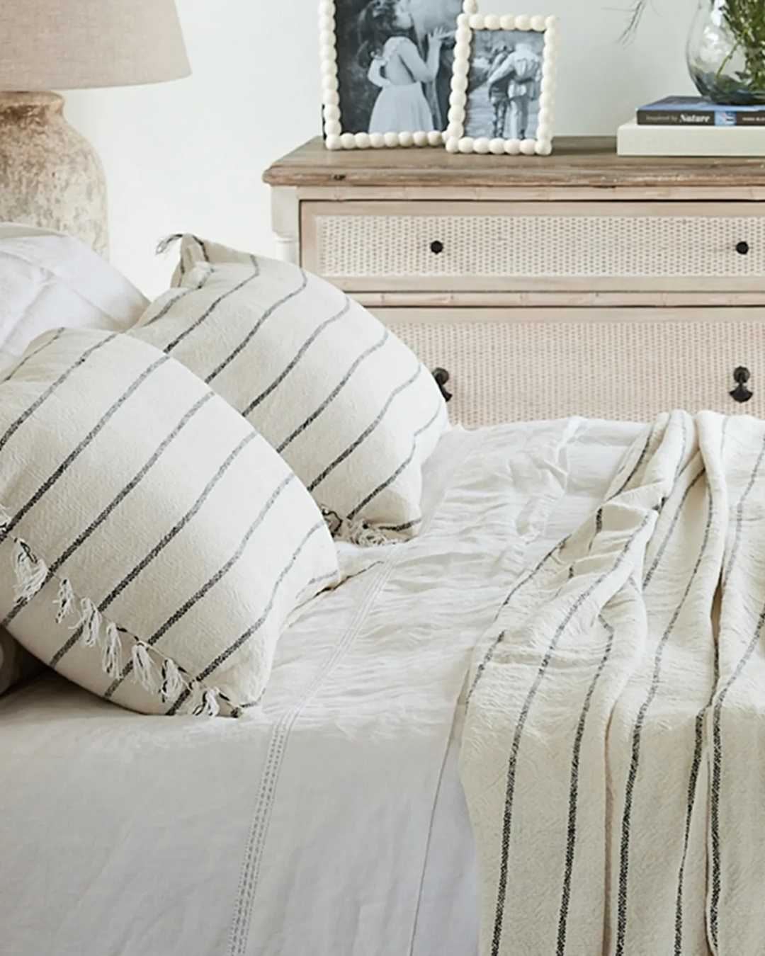 Striped linen cotton cushions on bed with striped cover and white sheets