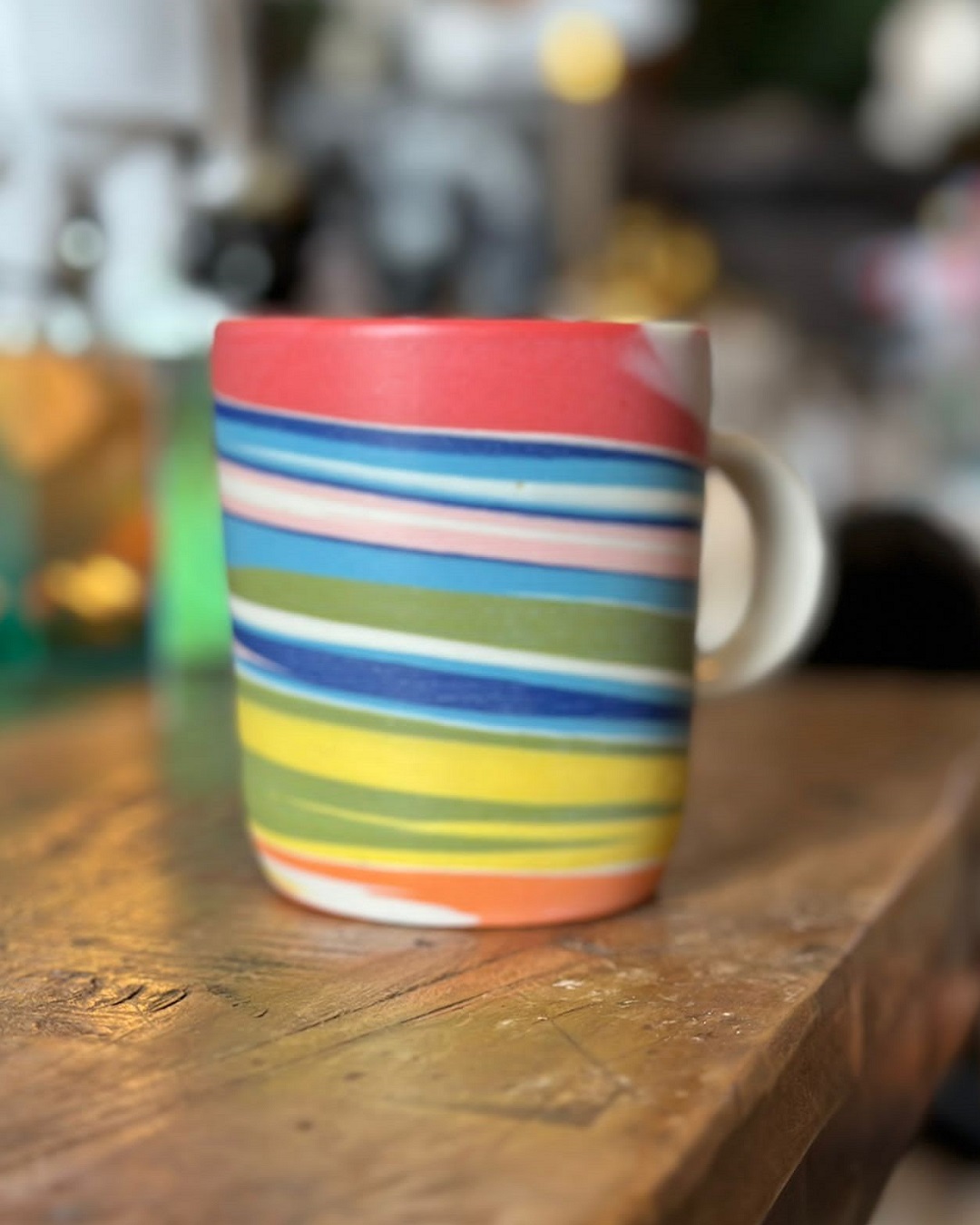 Thrown rainbow striped mug on wooden table