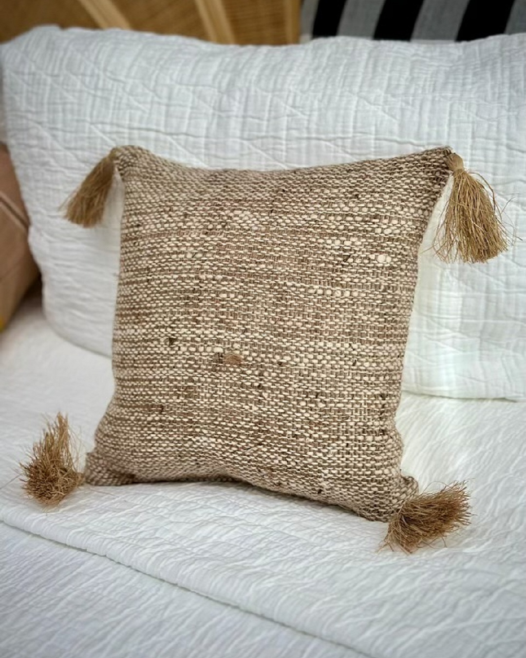 Woven cushion cover with tassels on bed