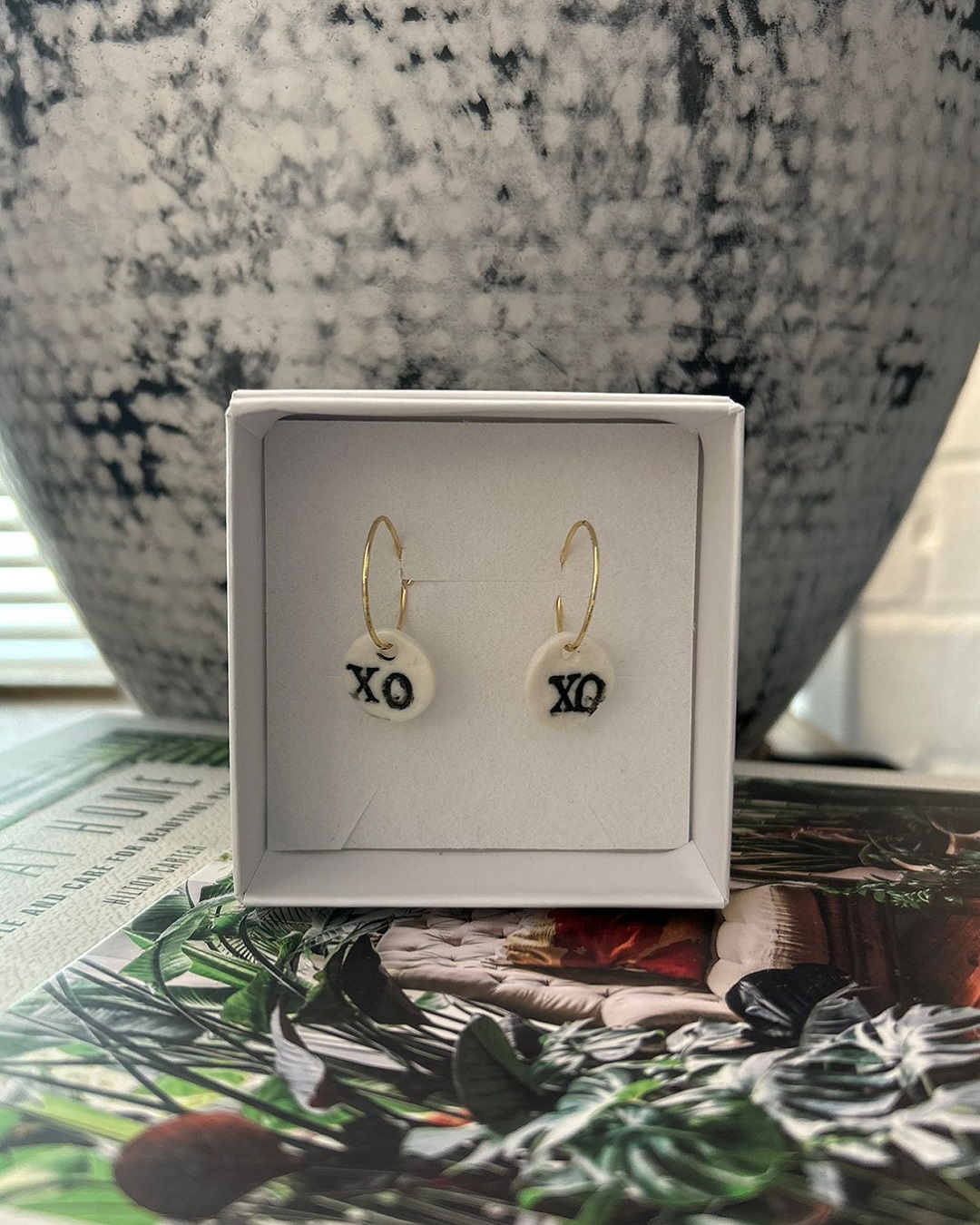 XO black on white circle earrings hanging in a box